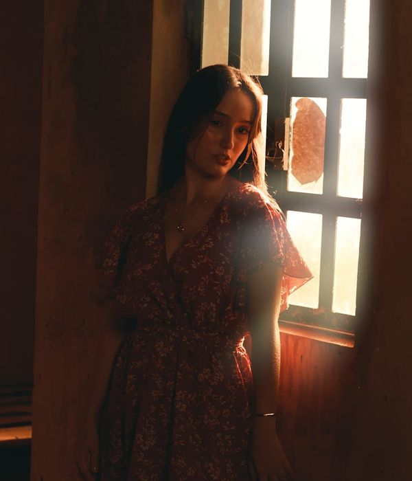Woman in a calm, meditative pose in a softly lit room.